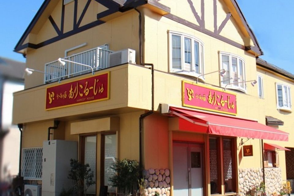 赤い看板が特徴的な店の外観写真