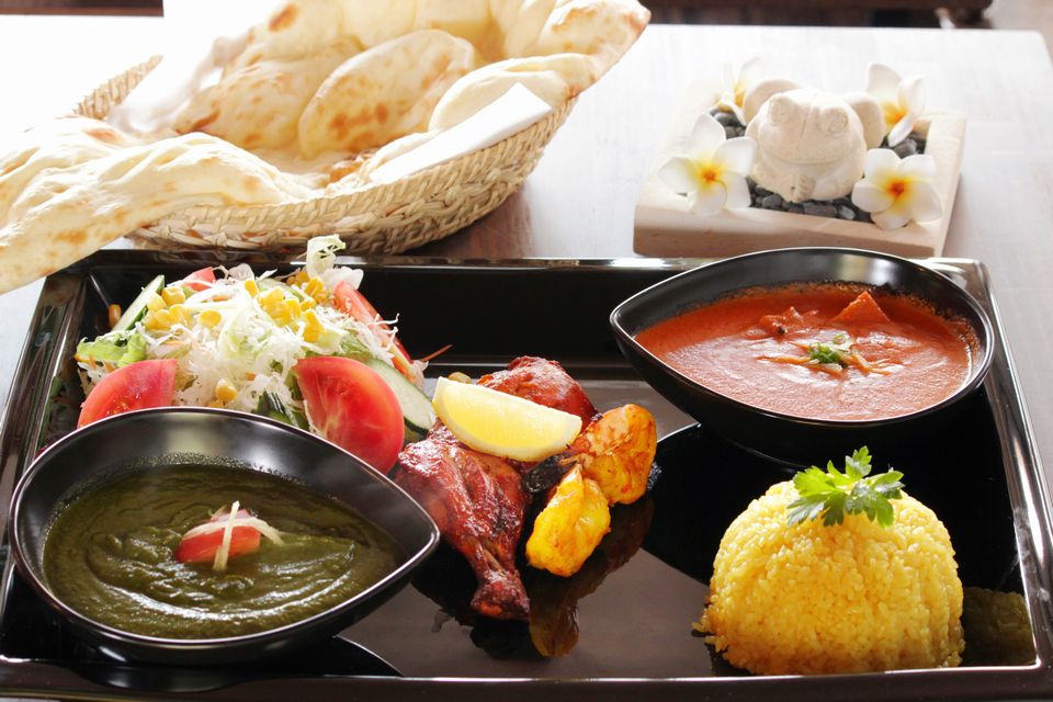 籠に乗ったナンとプレートに乗ったサラダやカレーの写真