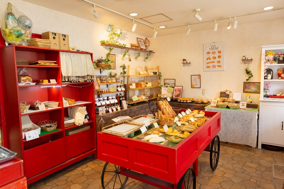 赤い棚やカートにパンが並べられている店内の写真