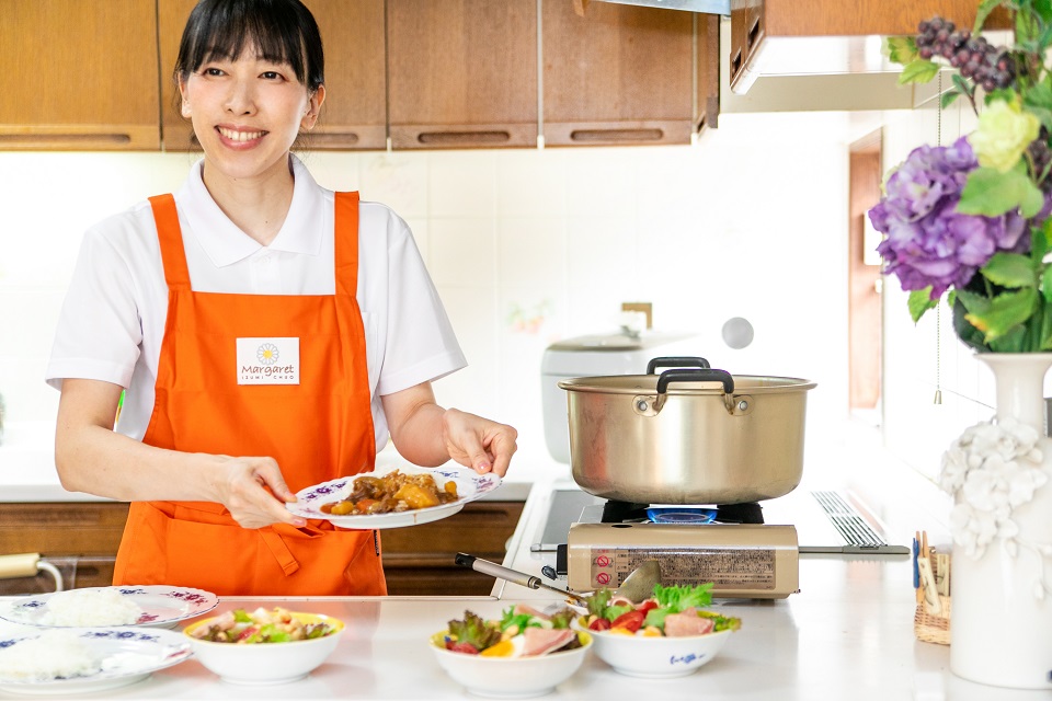 サラダやカレーを準備しているスタッフの女性の写真