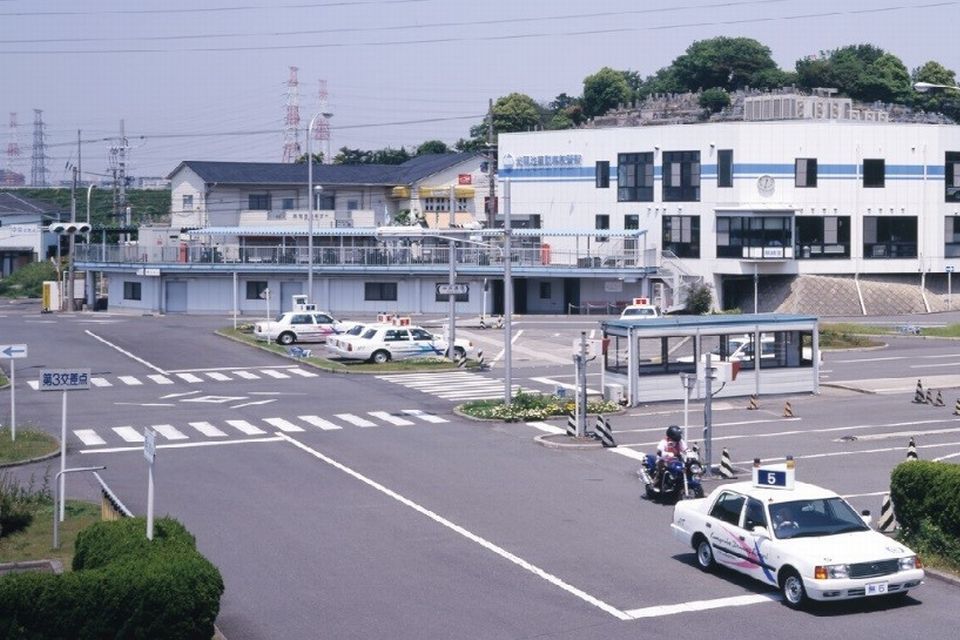 白い車が走る教習所内の車道の様子の写真