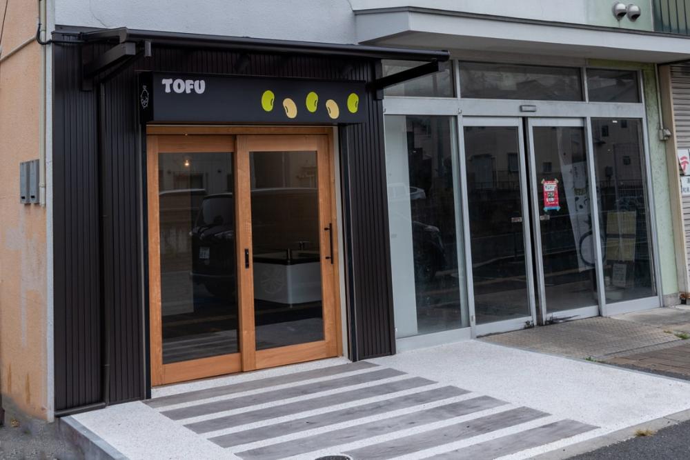 黒い壁に「TOFU」と書かれた看板が目印の店の外観写真