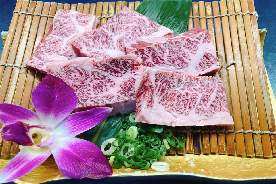 簀の子に乗せられた霜降り肉と花の写真