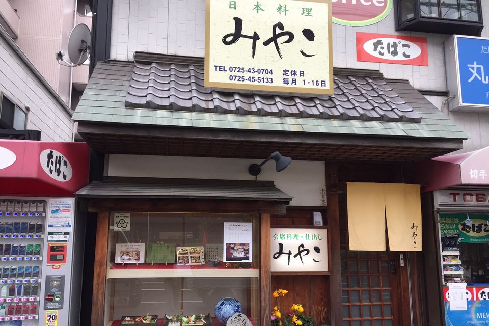 たばこの自販機の隣にある「みやこ」の看板が目印の建物の写真