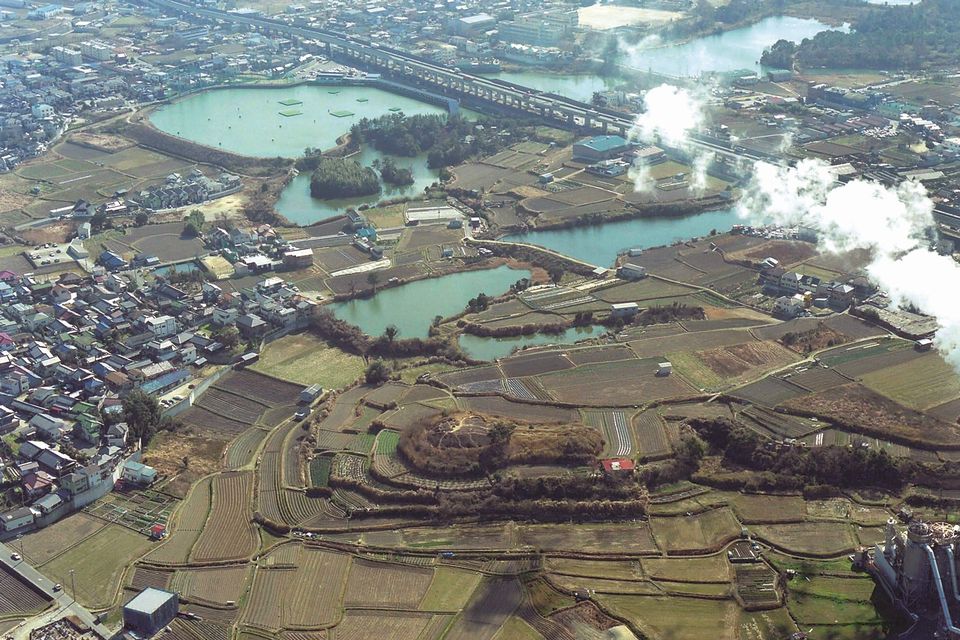 上空から撮影された畑に取り囲まれた前方後円墳の写真