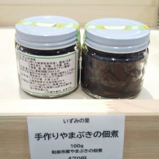 蓋が白、丸いガラス瓶に入った手作りやまぶきの佃煮の商品の商品名が書かれた正面に置いた商品と、ラベルが貼られていない商品を写した写真