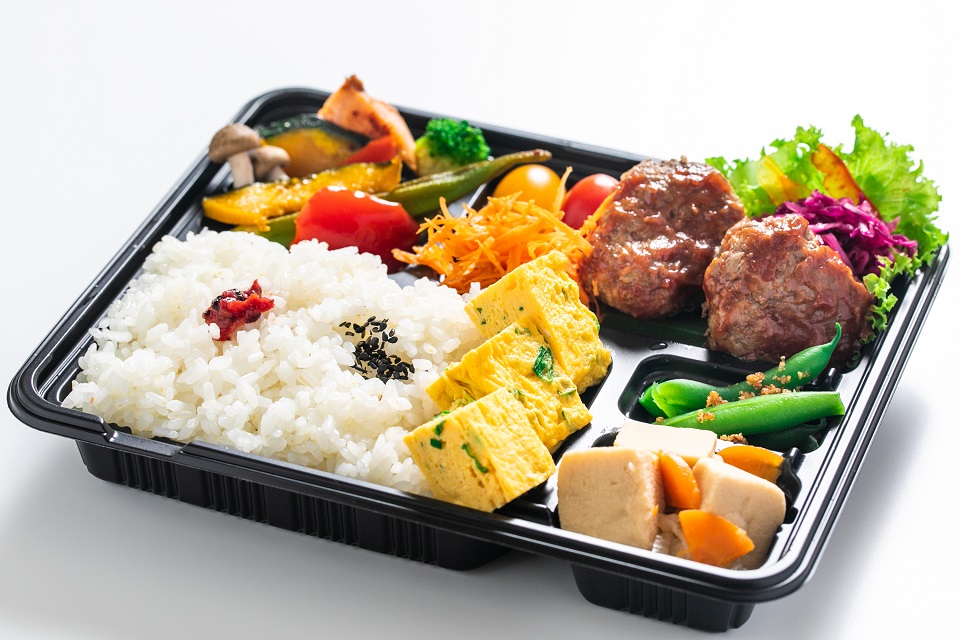 ハンバーグや卵焼き、煮物など野菜たっぷりのお弁当の写真