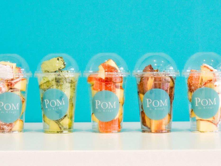 ロゴマークと様々なフレーバーのカップ入りりんご飴の写真