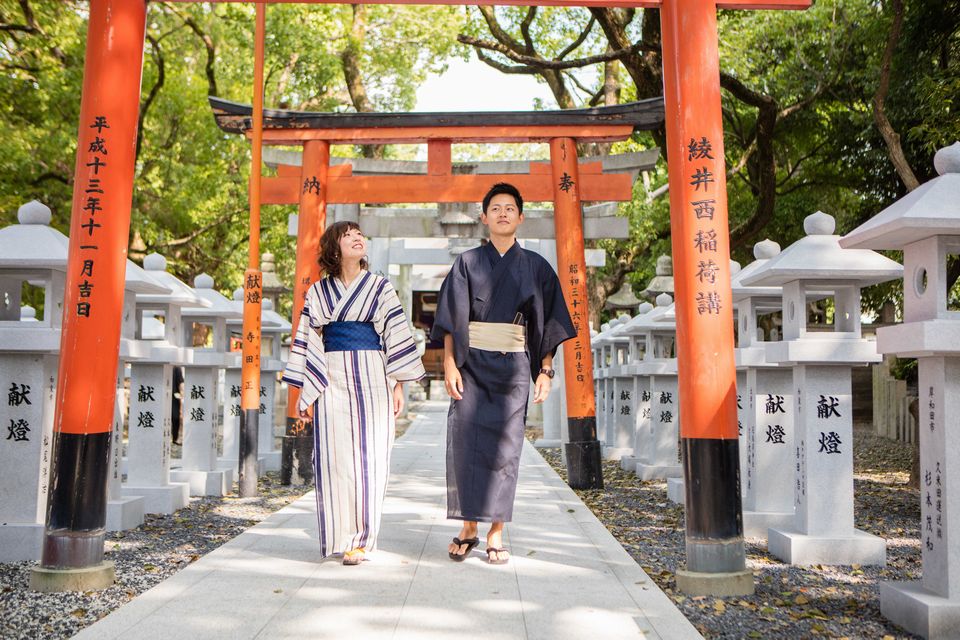 鳥居の下の道を歩く浴衣を着た男女の写真
